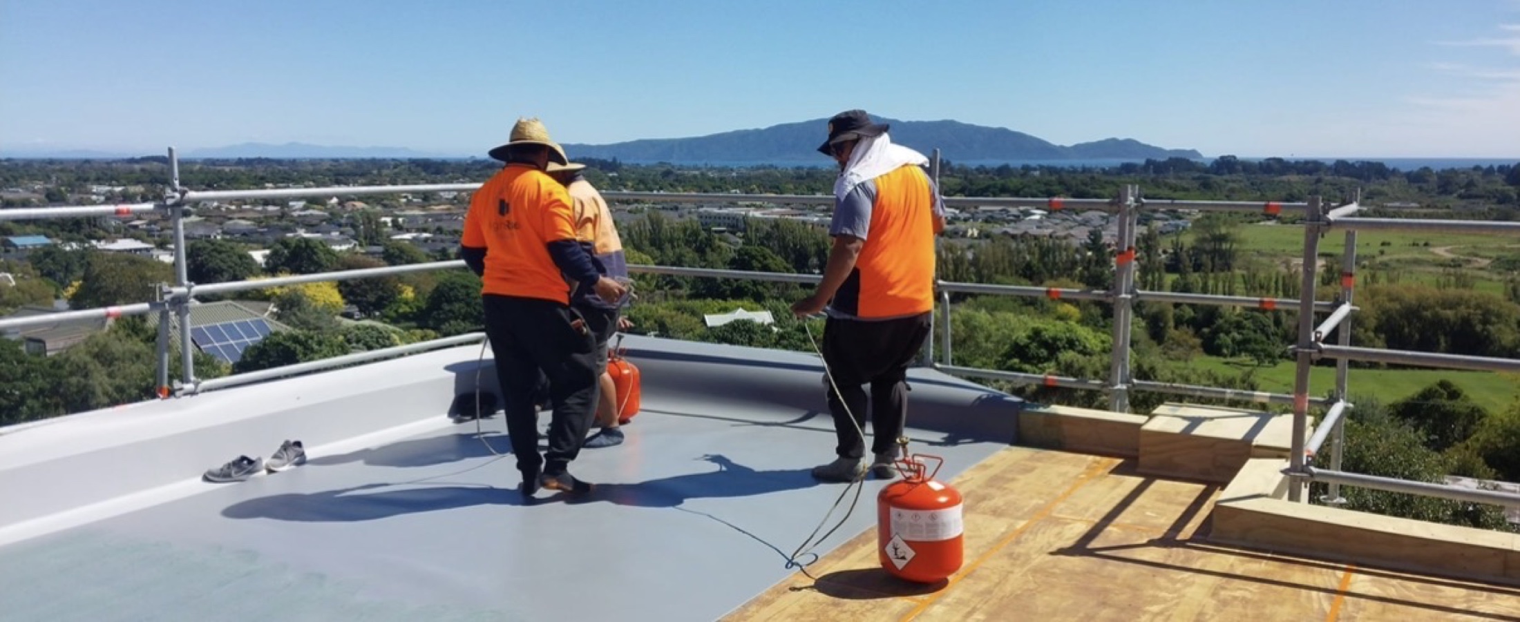 Highrise crew installing membrane on a Wellington roof